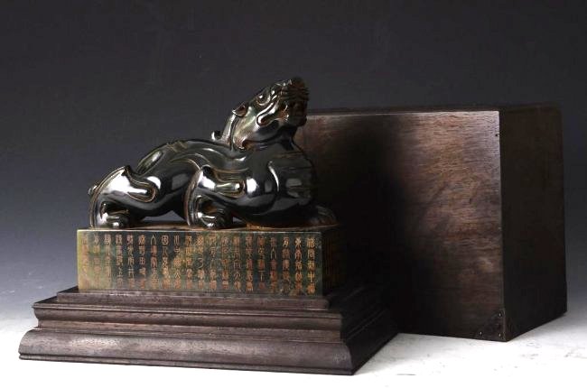 Chinese Jade Chiling Seal in Carved Wood Box: Long Chinese Jade Chiling Seal in Carved Wood Box. Finely carved jade chiling with dark wood box carved with calligraphy; H: 10 Inches for the box, L: 9 Inches for the Chiling