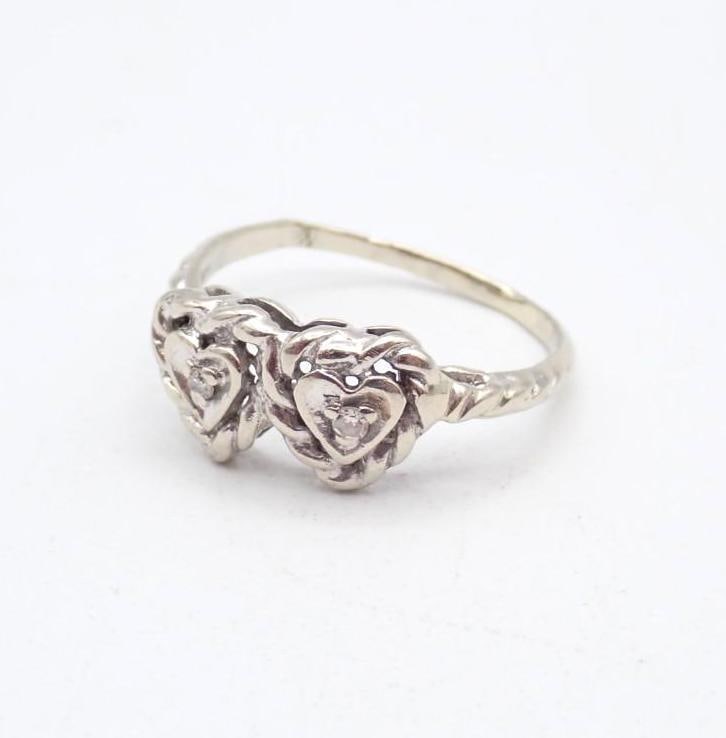 14K White Gold and Diamond Ring: with (2) 1.6mm round cut diamonds in heart form settings, size 7.25. 2.35 grams total weight