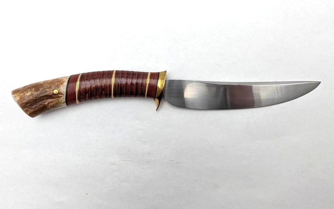 R.L. Welling Scagel Style Fixed Blade Knife: features a stacked leather handle with brass, red coral and white micarta spacers, stag pommel inset with a gold arrowhead, in a tooled leather R.L. Welling sheath with a silver concho. In beautiful