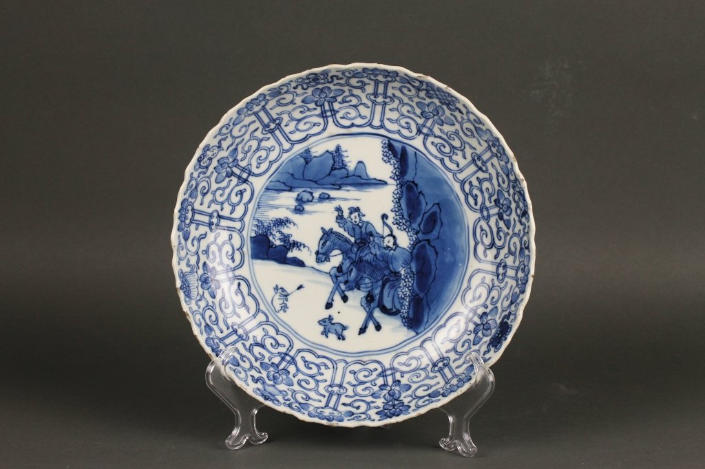 Chinese Kangxi Period Blue and White Plate: Chinese Kangxi Period 1662-1722 and of the period blue and white molded plate painted with the much collected Mongolian Hunting Pattern. the center of the plate shows a lady and attendant in a mountai