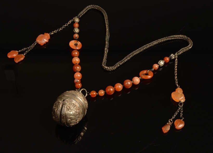 Chinese Qing Silver Carved Carnelian Necklace: Chinese Qing dynasty silver and carved carnelian necklace. The pendant being a silver bell with a butterfly and floral decoration. The necklace with lage carnelian beads as well as carved circular rin