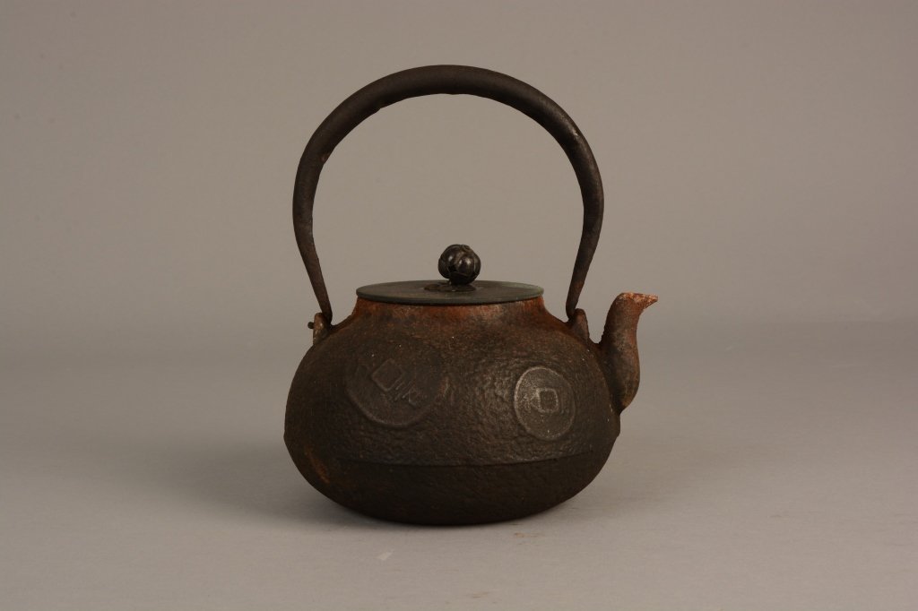 Antique Japanese Bronze and Iron Teapot: Antique Japanese iron and bronze teapot with coin motif; lid signed to the underside; measures 9" tall.