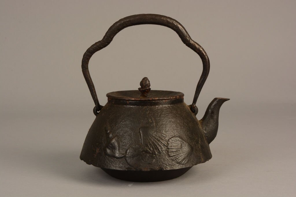 Antique Japanese Cast Iron Teapot: Antique Japanese Cast Iron teapot with shell motif. Character mark to side; measures 8" tall.