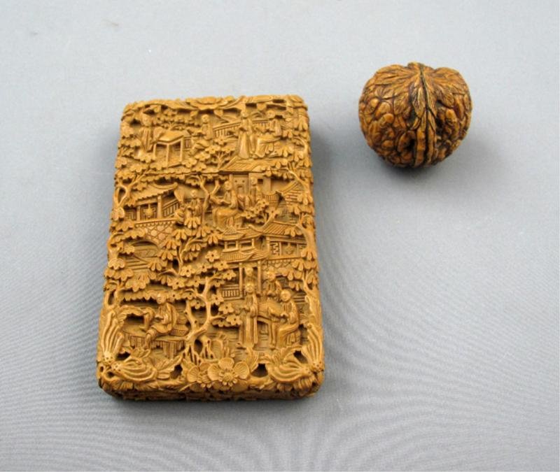 CARVED SANDALWOOD CARD CASE & CARVED WALNUT: - rectangular Chinese card case carved with allover relief of figures amidst dwellings and trees together with carved walnut. Card case: 4 1/4 x 2 3/4 x 3/4 in. (10.7 x 6.9 x 1.9 cm)