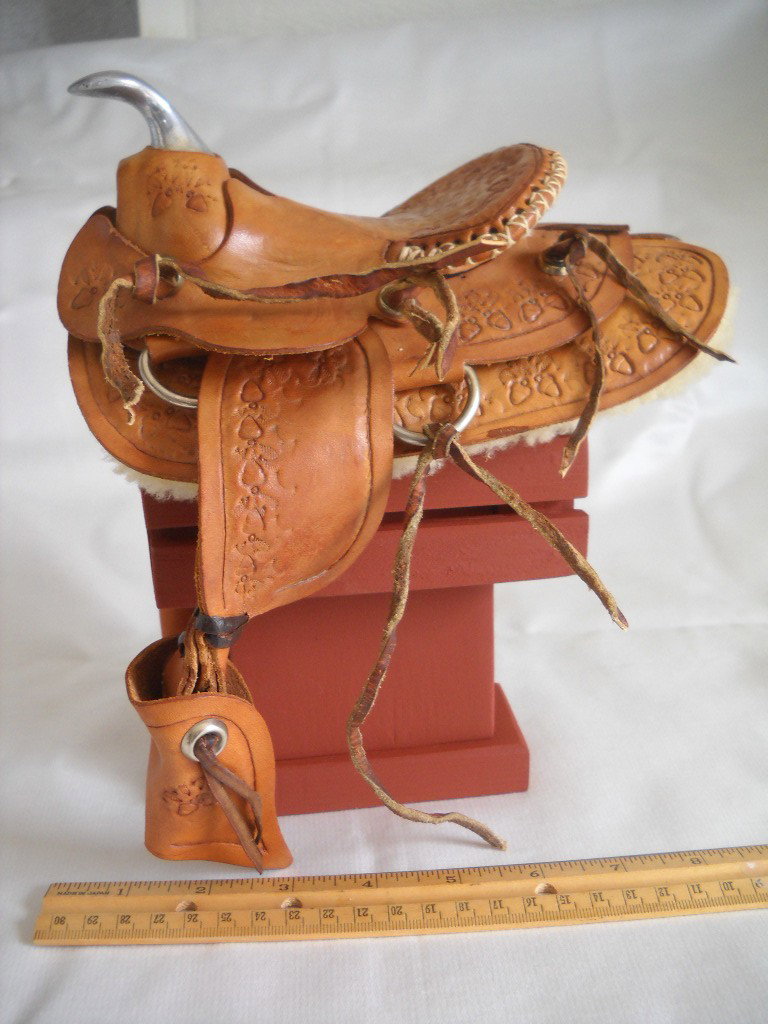 Cowboy Gear: Miniature Saddle and Wood Saddle Rack, approx 7"inches high. Stamped with acorn motifs and metal saddle horn. Very good condition.