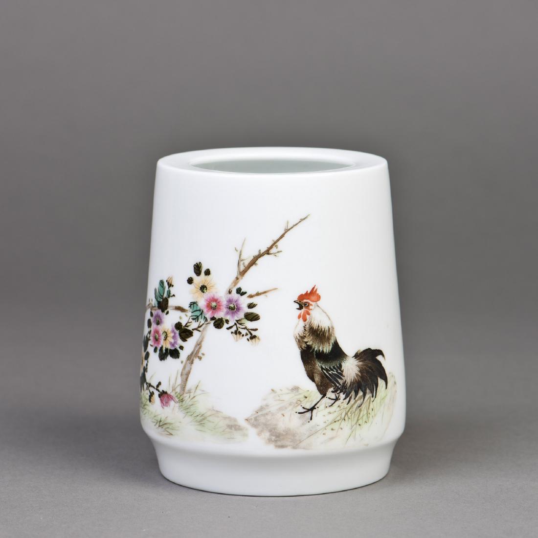A FAMILLE ROSE PORCELAIN BRUSH POT: A famille rose porcelain brush pot featuring a slightly tapered body towards a retracted mouth rim, with a painting depicting a rooster next to blooming flowers, Chinese calligraphy inscription on one