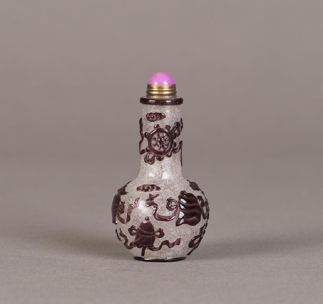 A PEKING GLASS SNUFF BOTTLE: A well proportioned peking glass snuff bottle with dark brown glass relief of auspicious foliage and animals, pink glass and golden metal stopper. Height 3.5" Width 1.75"