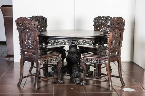 CHINESE ROUGE MARBLE-INSET TABLE AND FOUR CHAIRS: A Chinese carved hardwood or zitan center table, 19th century, with inset marble top on elaborate pierce carved tripod base ending in paw feet, from a English family estate. The four back panels pierc