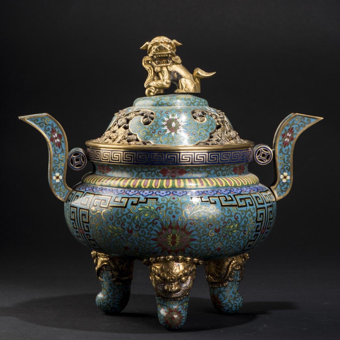 AN ARCHAISTIC CLOISONNE GILTED CENSER: Of handled bombe-form, raised upon three beast-like head legs and surmounted by a domical lid of reticulated gilt bat and smoke patterns beneath a fu lion dog finial. Height 9'' Width 10''