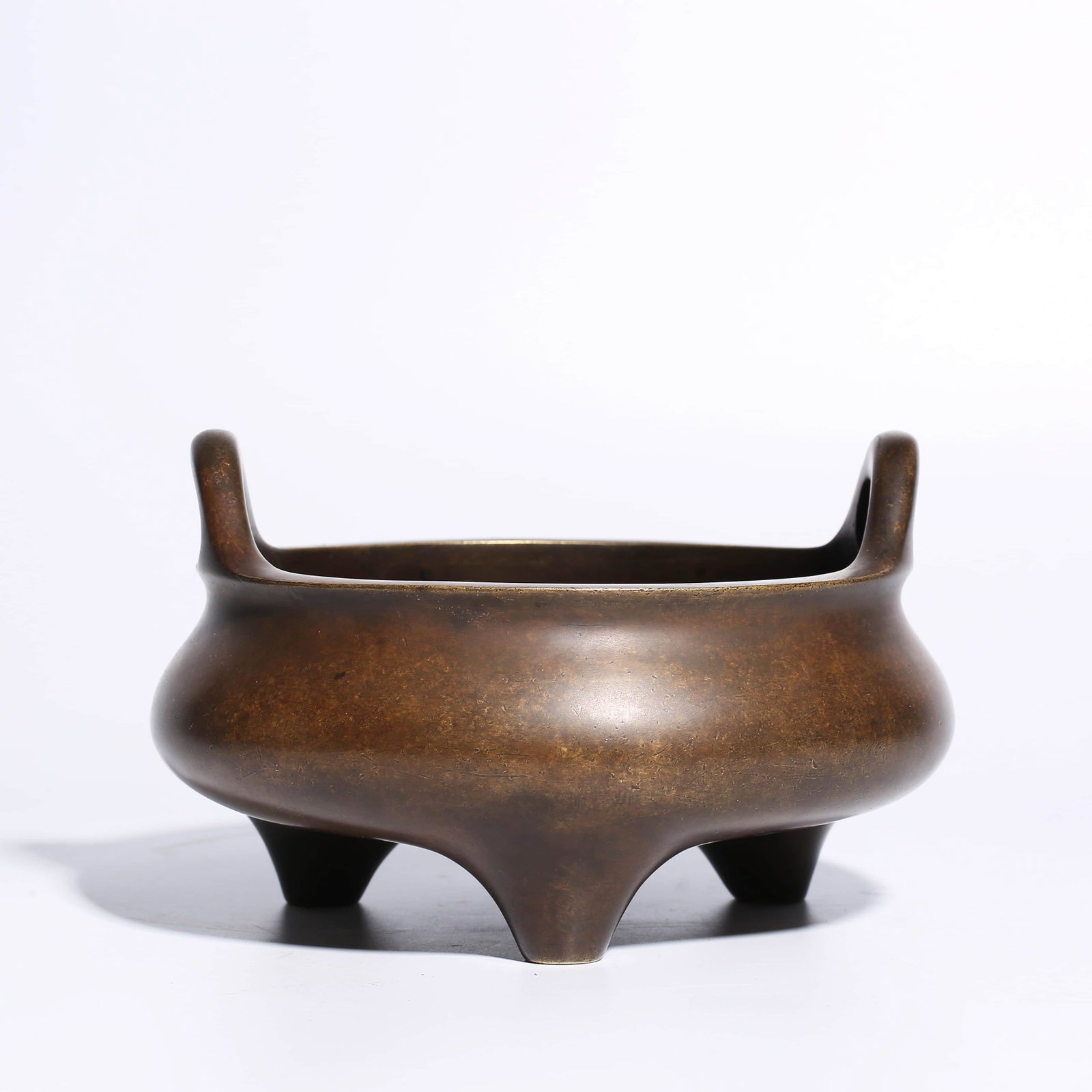 A CHINESE BRONZE CENSER: The censer is heavily cast with a compressed globular body inscribed to one side, flanked by twin handles and supported on three short feet.Diam.18.3cm, Height:12.5cm,