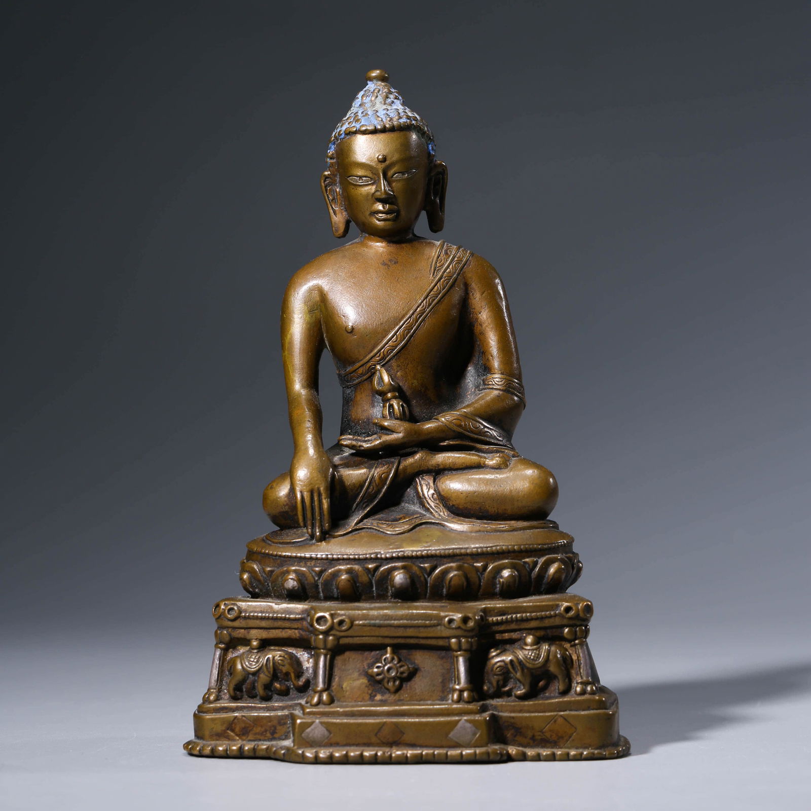 A CHINESE BRONZE SAKYAMUNI STAUTE: The figure is carved seated in dhyanasana and dressed in long flowing robes tied at the waist. The face is carved with downcast eyes and a serene expression. Weight:572g, Length:10.3cm, Width:7.6cm, H