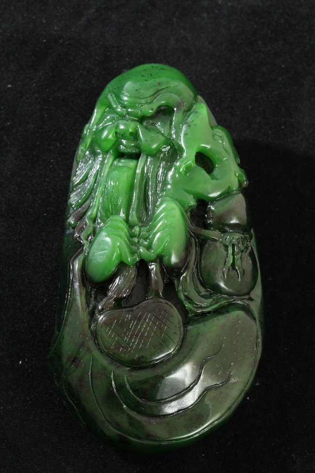 Unusual Nephrite Green Jade Old Man: A spectacular nephrite green jade carved as a happy old man, smiling and holding a longevity locket pendant with both hands, a gourd tucked under his arm. The surface of reversed side carved with a fl