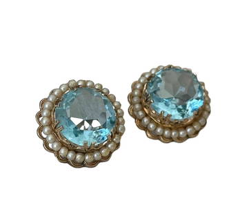ICE CRYSTAL BLUE GLASS EAR CLIPS: ICE CRYSTAL BLUE GLASS EAR CLIPS A pair of clip-on earrings featuring ice crystal blue glass stones as the focal point. Surrounded by a row of faux pearls, the design adds a touch of elegance. The bac