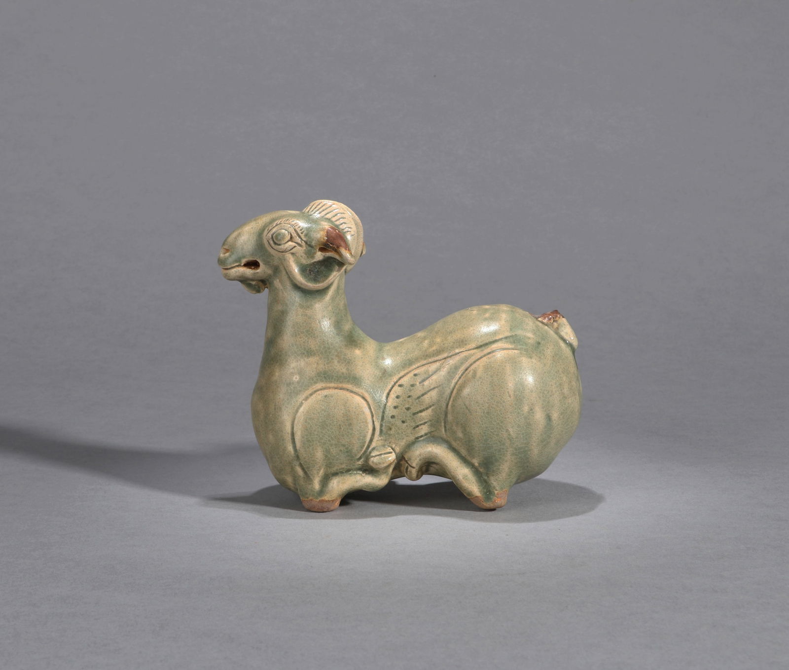 A YUEYAO CELADON RAM: A Yueyao celadon figure of a recumbent ram. Length 13 cm, Height 12 cm.