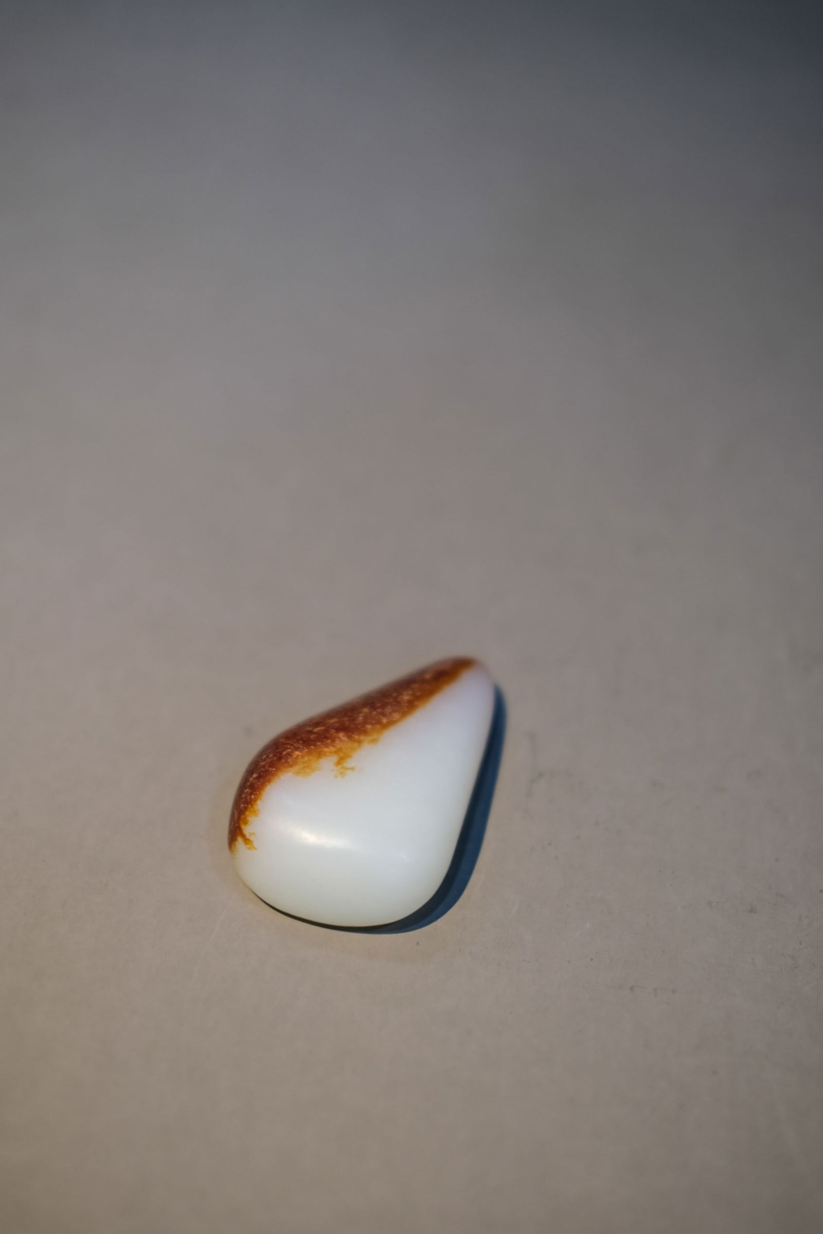 WHITE AND RUSSET JADE OVAL STONE: White and russet jade oval stone. Dimensions: Length: 5.6 cm, Width: 3.6 cm.