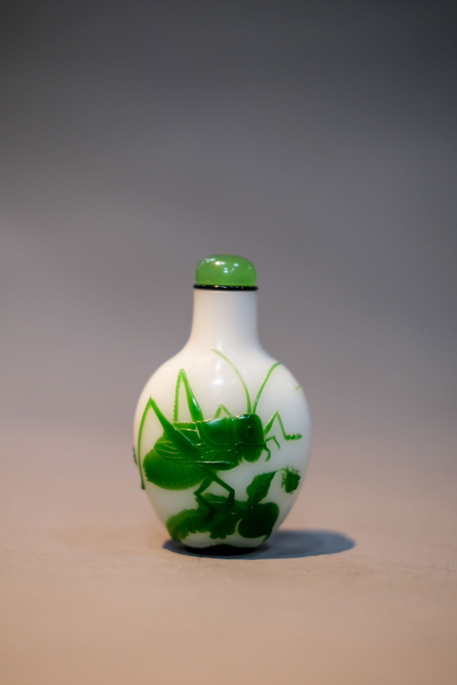 GREEN OVERLAY WHITE GRASSHOPPER SNUFF BOTTLE: Green overlay white grasshopper snuff bottle. Dimensions: Height: 7.5 cm.