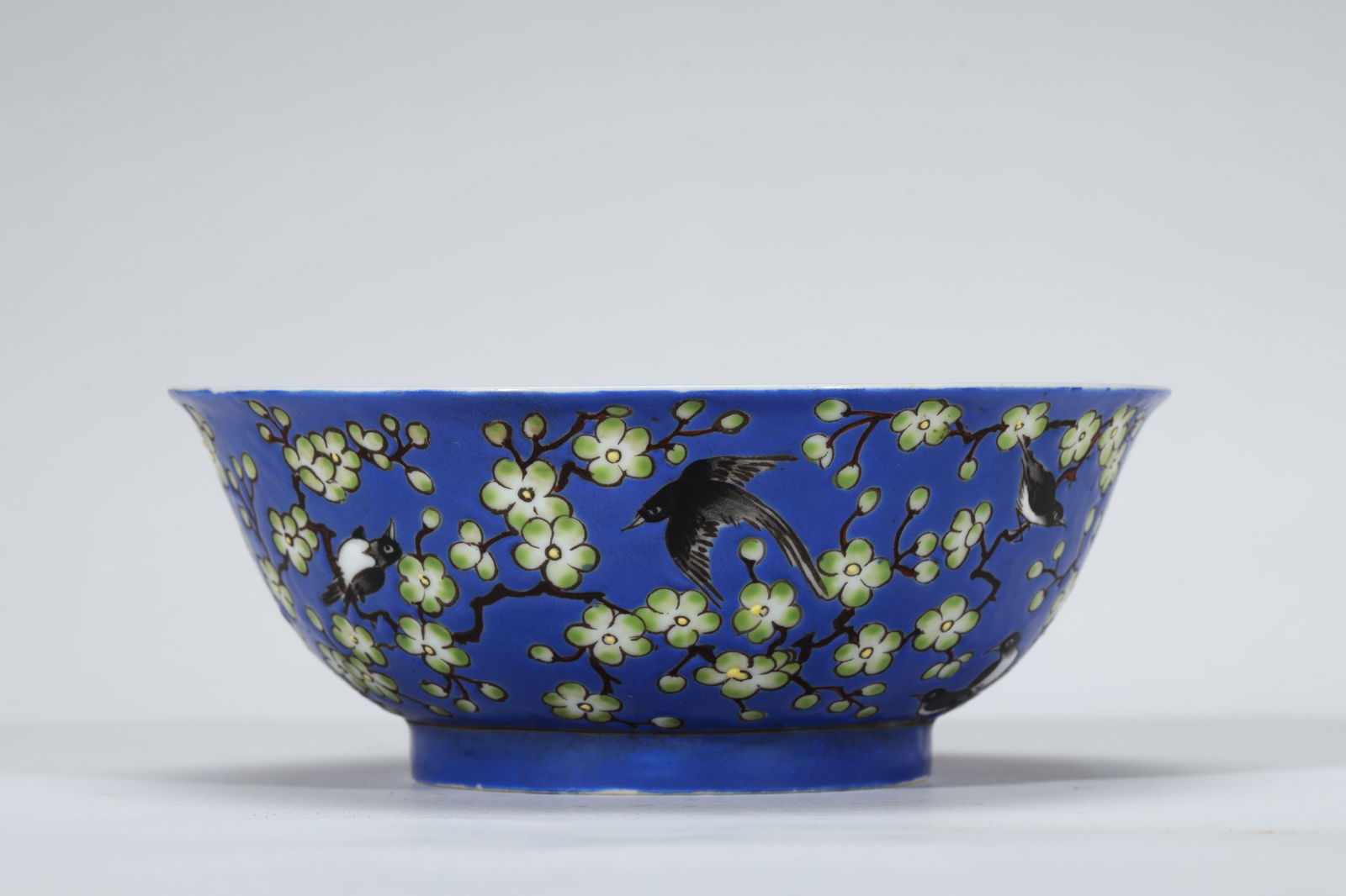 BLUE GROUND FAMILLE ROSE PRUNUS AND MAGPIE BOWL: Blue ground famille rose Prunus and Magpie bowl. Dimensions: Diameter: 14.2 cm, Height: 5.5 cm.