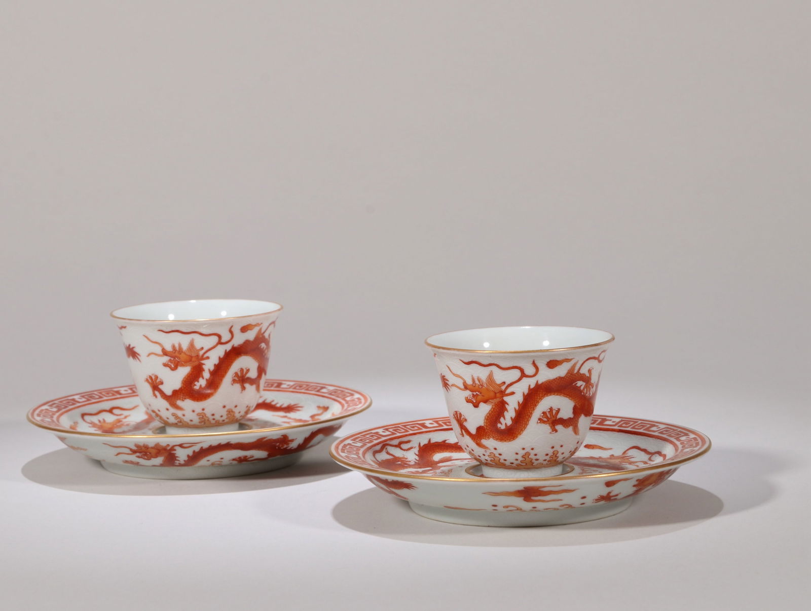 AN IRON-RED AND WHITE CUP AND STAND: An iron-red cup and stand decorated with reserved white cloud and dragon design.Diameter 12 cm.