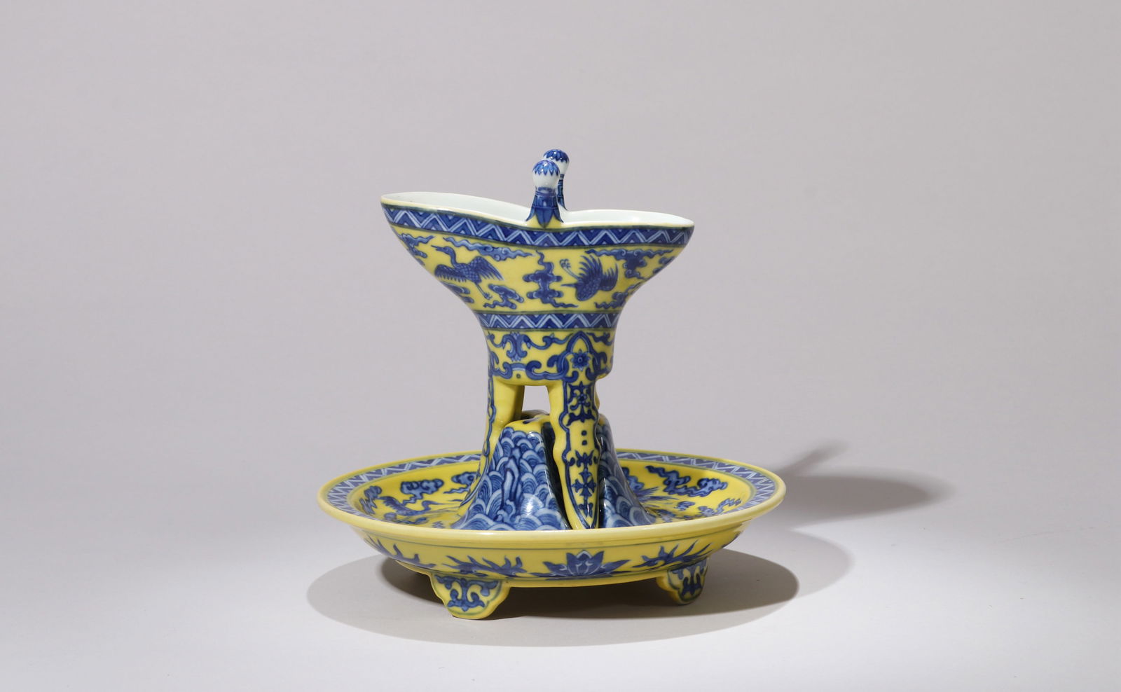 A YELLOW-GROUND BLUE AND WHITE CUP: A yellow-ground blue and white Jue cup decorated with cloud and crane design.Height 17.5 cm, Diameter 17.5 cm.