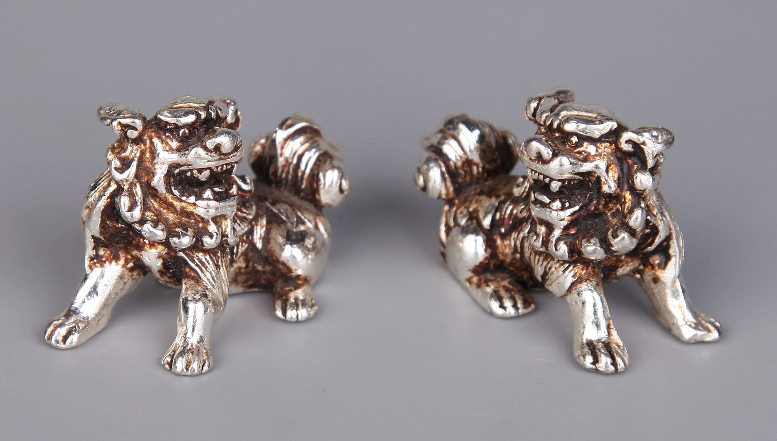 A PAIR OF GILT-SILVER LIONS: A pair of gilt-silver lion ornaments.Height 3 cm.