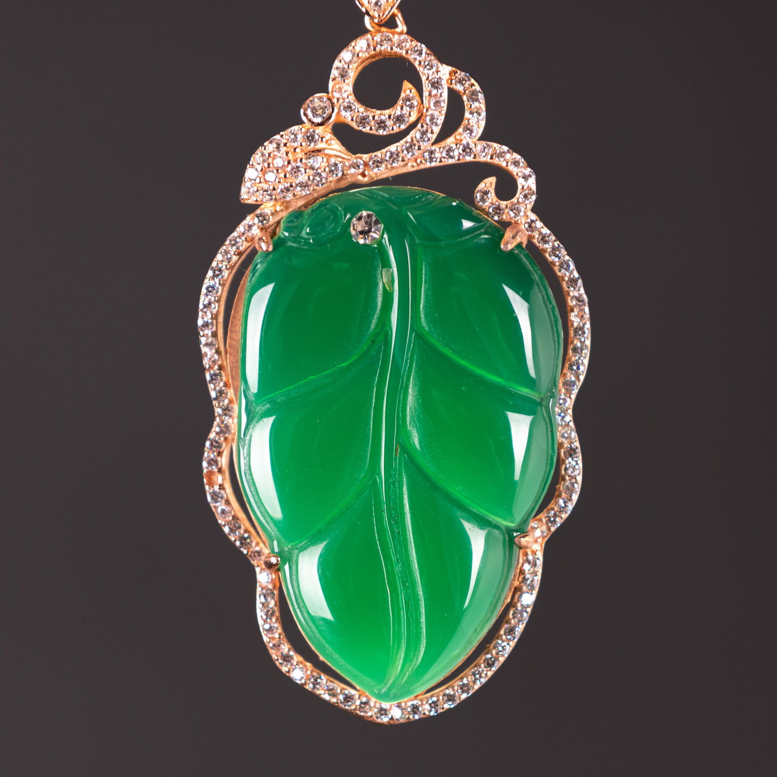 A JADE PENDANT: A jade pendant mounted in rose gold with multi-brilliant crystals.4.1 x 2.5 cm.