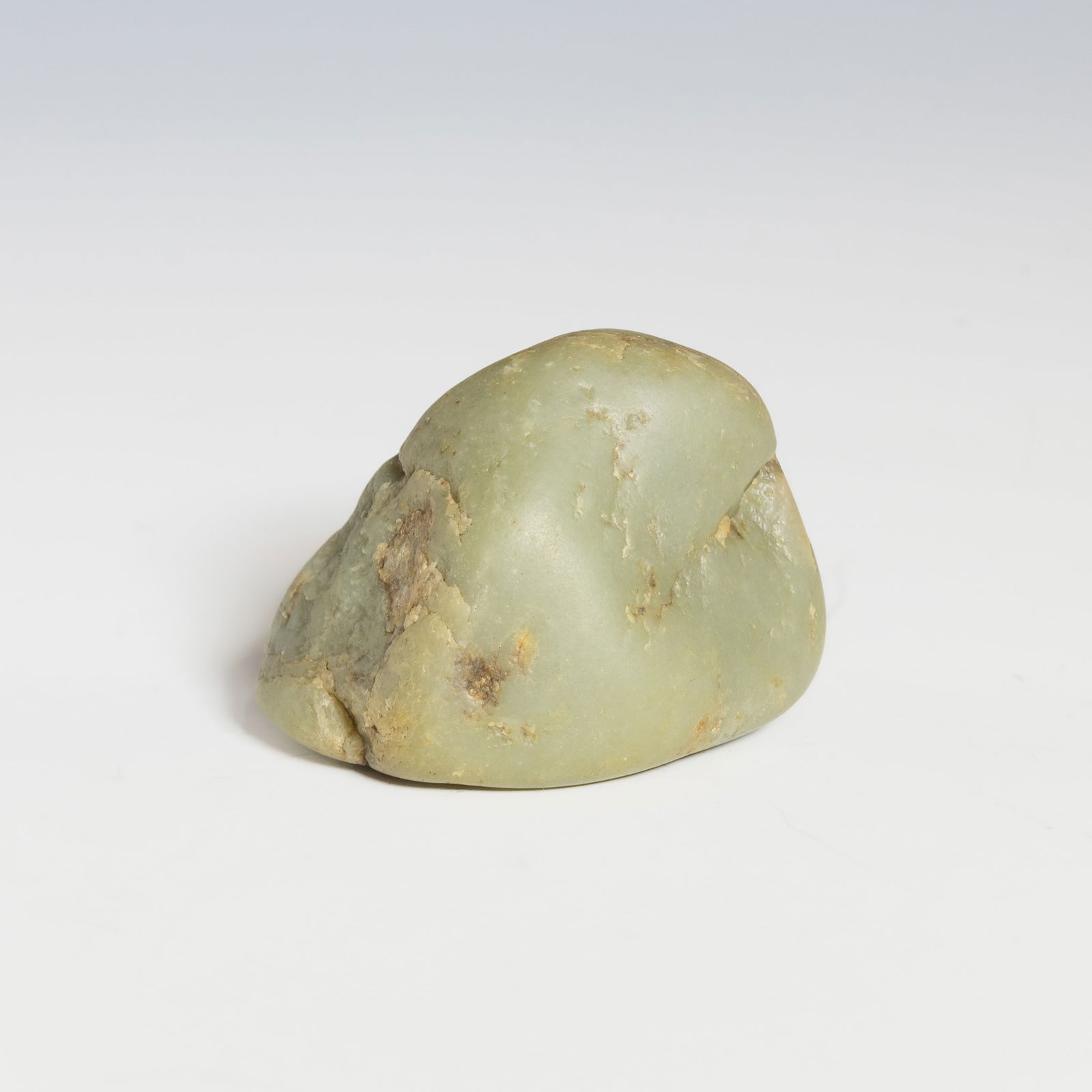 HETIAN JADE PEBBLE STONE: A Hetian jade pebble stone, natural, uncarved form with a smooth surface and warm tone.Dimensions: 2.95"h x 3.94"w x 2.76"l (7.5 x 10 x 7 cm)Weight: 694 g