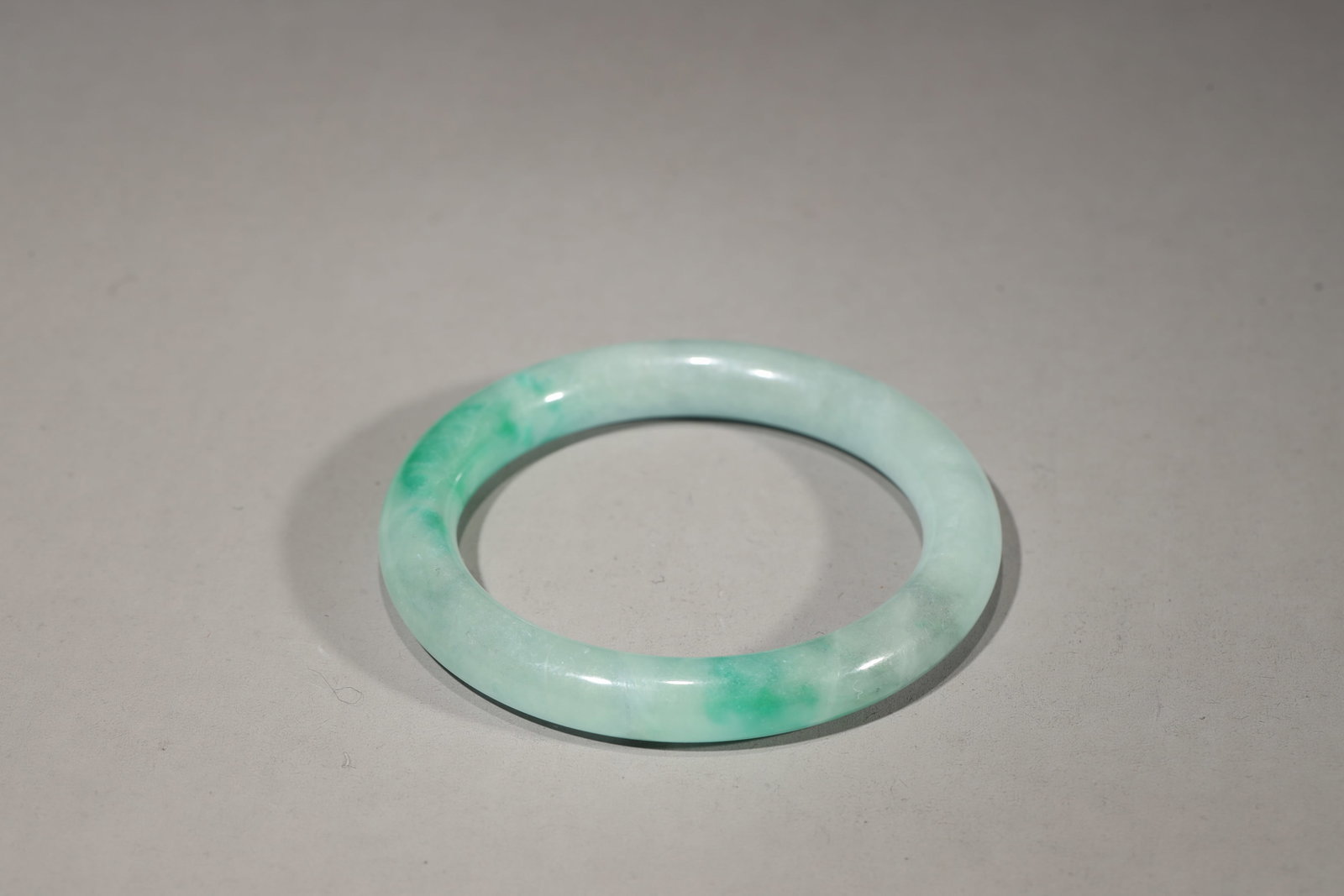A MOTTLED JADEITE BANGLE: A mottled jadeite bangle.Dimensions: Diam: 7.9 cm.