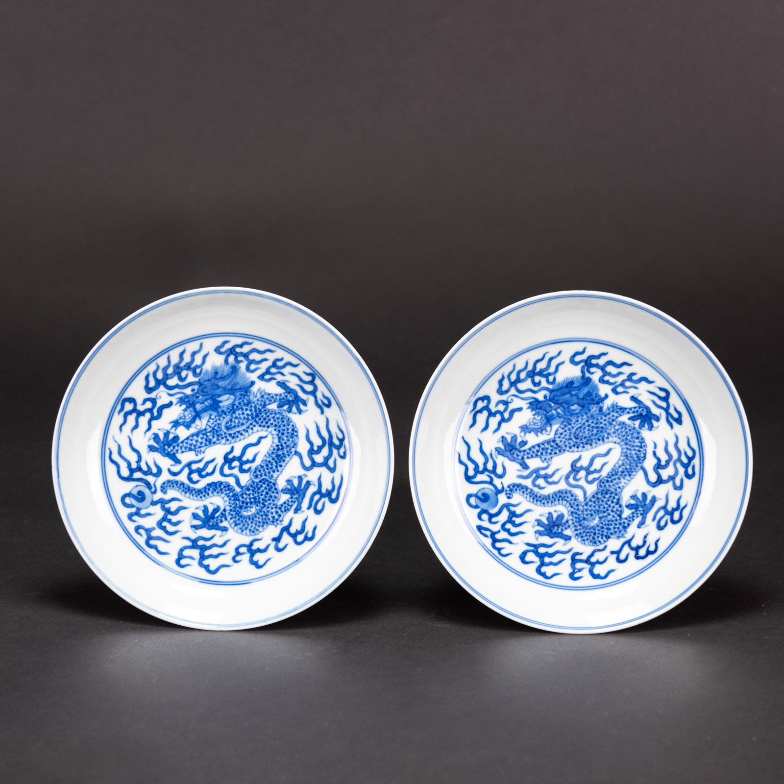 PAIR OF CHINESE BLUE AND WHITE 'DRAGON' DISHES: (lot of 2) Pair of Chinese blue and white 'dragon' dishes, each of shallow rounded form, interior decorated with a roundel of dragon pursuing a pearl amid flames and the exterior encircled by two