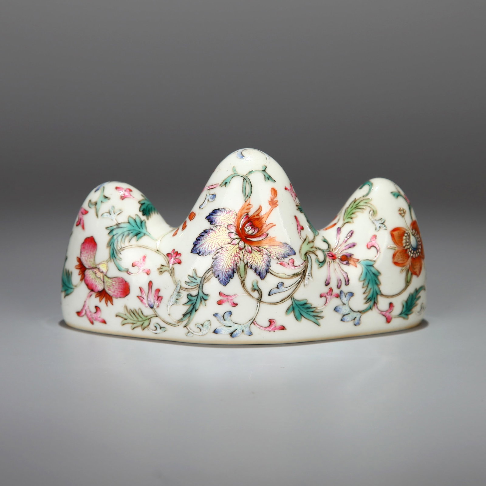 A FAMILLE-ROSE 'FLORAL' BRUSH REST: A famille-rose brush rest decorated with flowers. Height 6.5 cm, Length 12 cm.