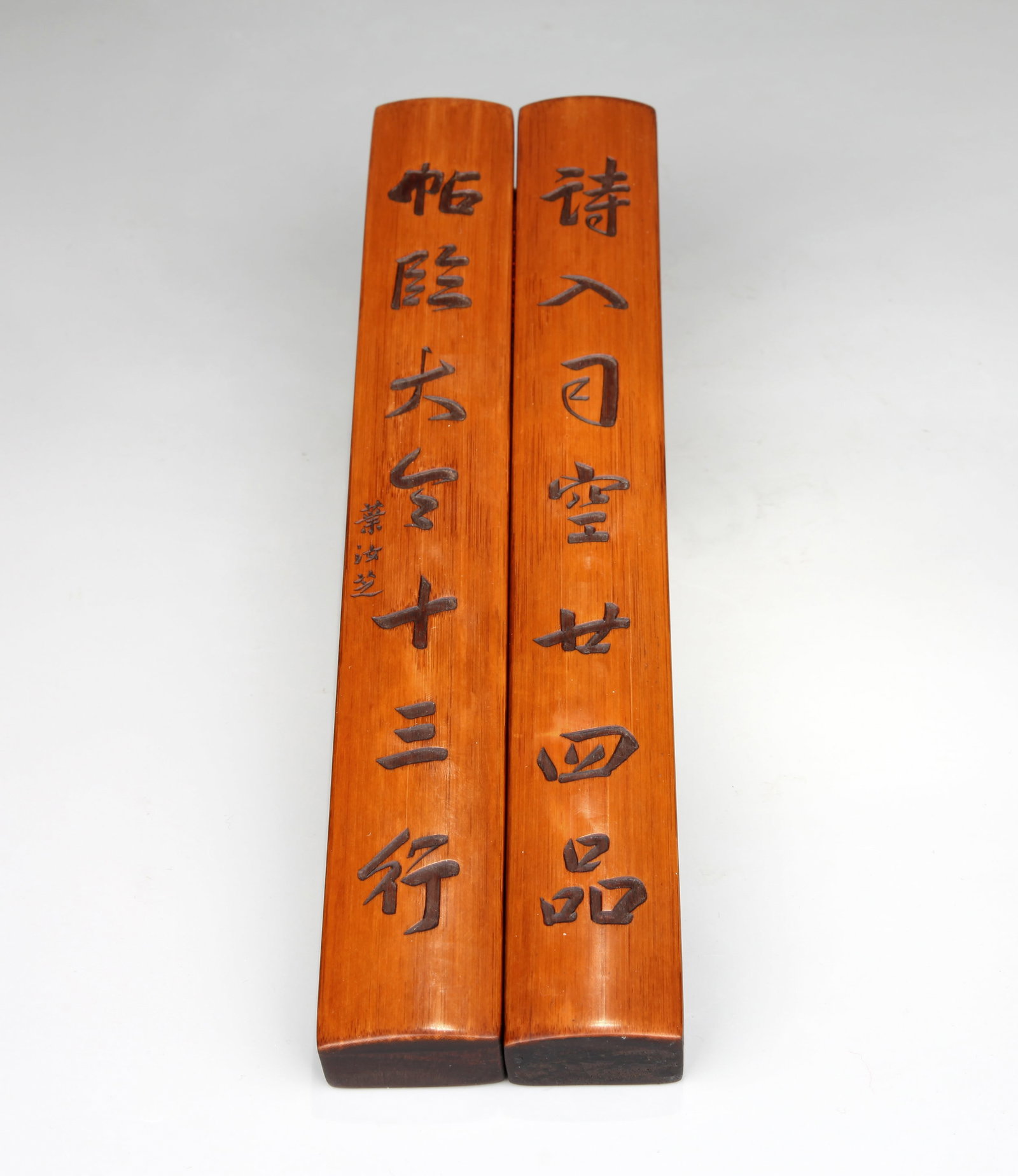 A WOOD AND BAMBOO PAPER WEIGHT: A redwood paper weight with bamboo veneer and poems. Length 29.8 cm, Width 3.8 cm, Height 2.5 cm.