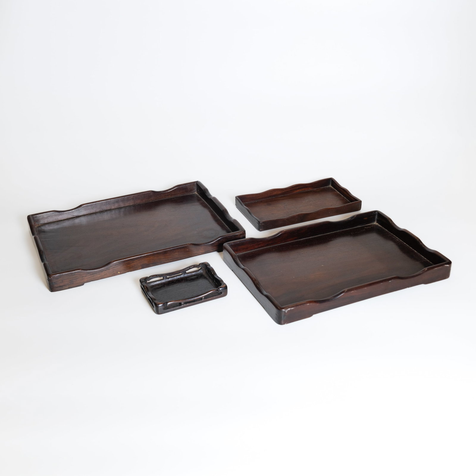 GROUP OF FOUR WOODEN TRAYS: (lot of 4) A group of wooden trays. Largest: 3 x 36 x 24.5 cm; smallest: 2 x 12.5 x 9 cm Provenance: Private collection of the Smith family, Santa Monica, California, by descent.