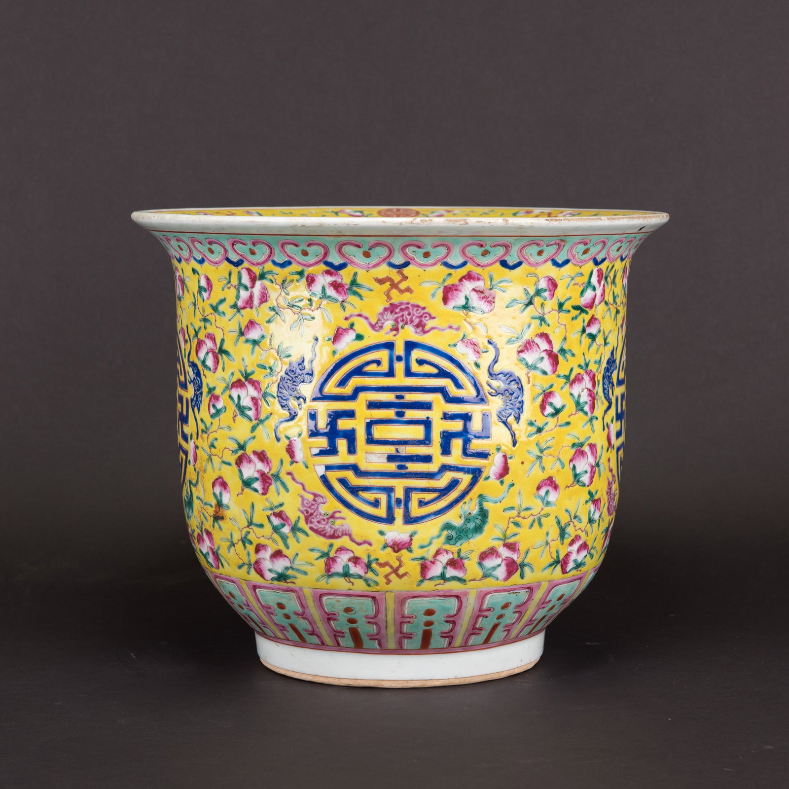A YELLOW GROUND FAMILLE ROSE "PEACH AND SHOU" JARDINIERE, 19TH CENTURY: A yellow ground famille rose "peach and shou" jardiniere, 19th century. The jardiniere is decorated to the exterior with five roundels of shou characters surrounded by peaches, all reserved on a brigh