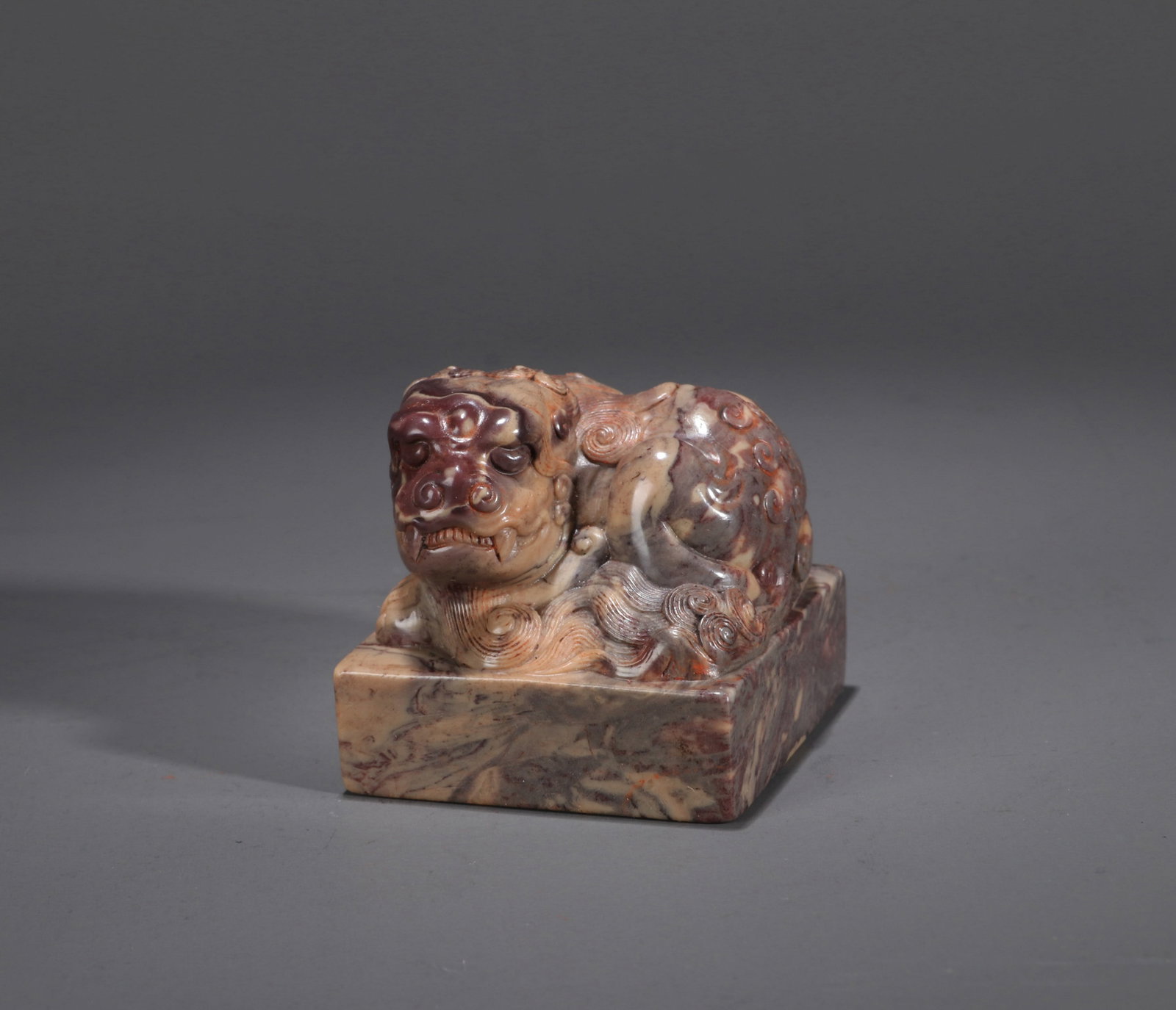 A SHOUSHAN STONE 'RECUMBENT LION' SEAL: A Shoushan stone seal surmounted by a recumbent lion finial, with an inscription reading 'Cheng Qinwang Bao'. 4 x 4 x 4 cm.