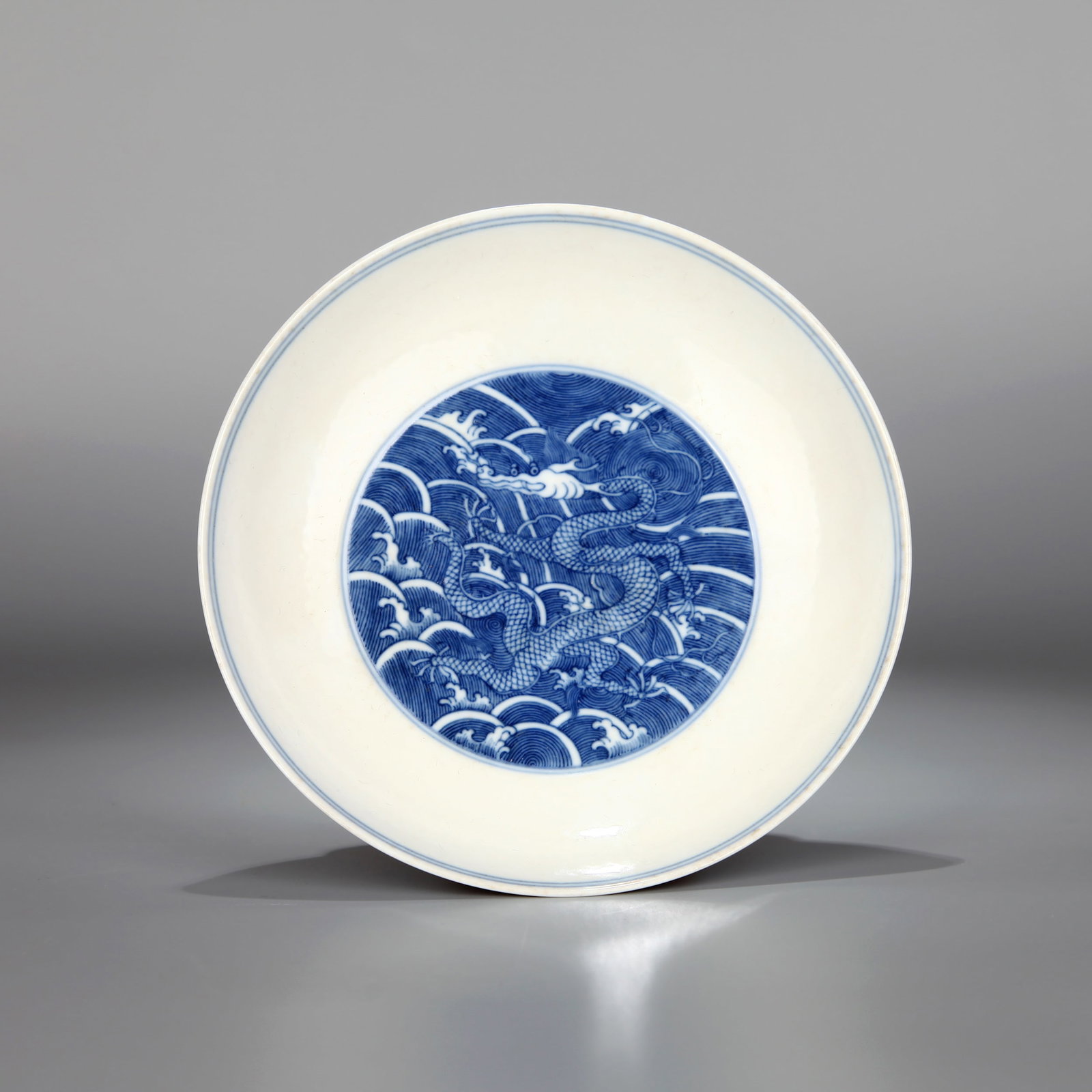 A BLUE AND WHITE RESERVE-DECORATED 'DRAGON' DISH: A blue and white dish decorated with a standing dragon reserved in white. Height 4 cm, mouth diameter 17 cm.