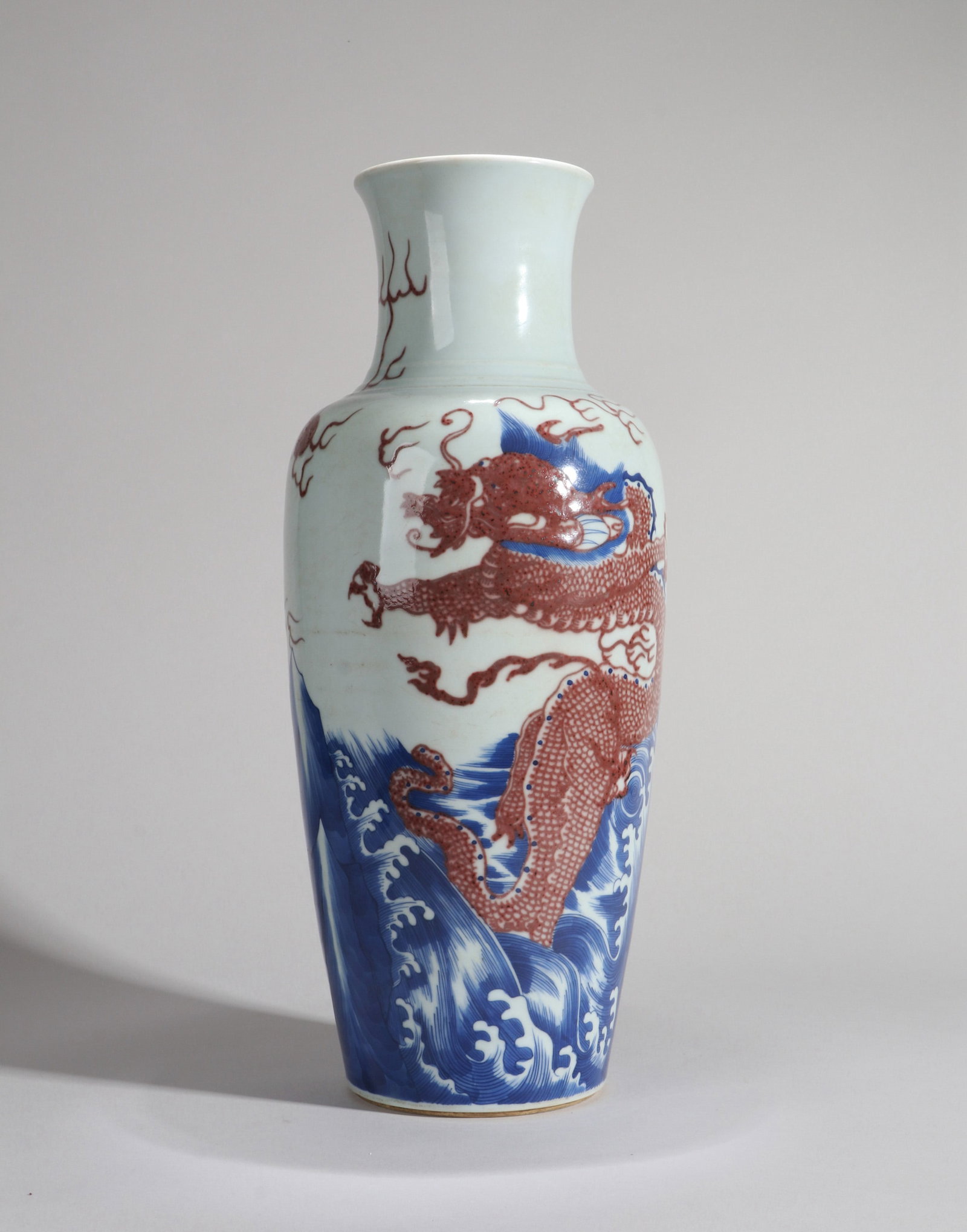 A BLUE AND WHITE AND UNDERGLAZE-RED 'DRAGON AMID WAVES' GUANYIN VASE: A blue and white and underglaze-red 'dragon amid waves' Guanyin vase. Height 43 cm.