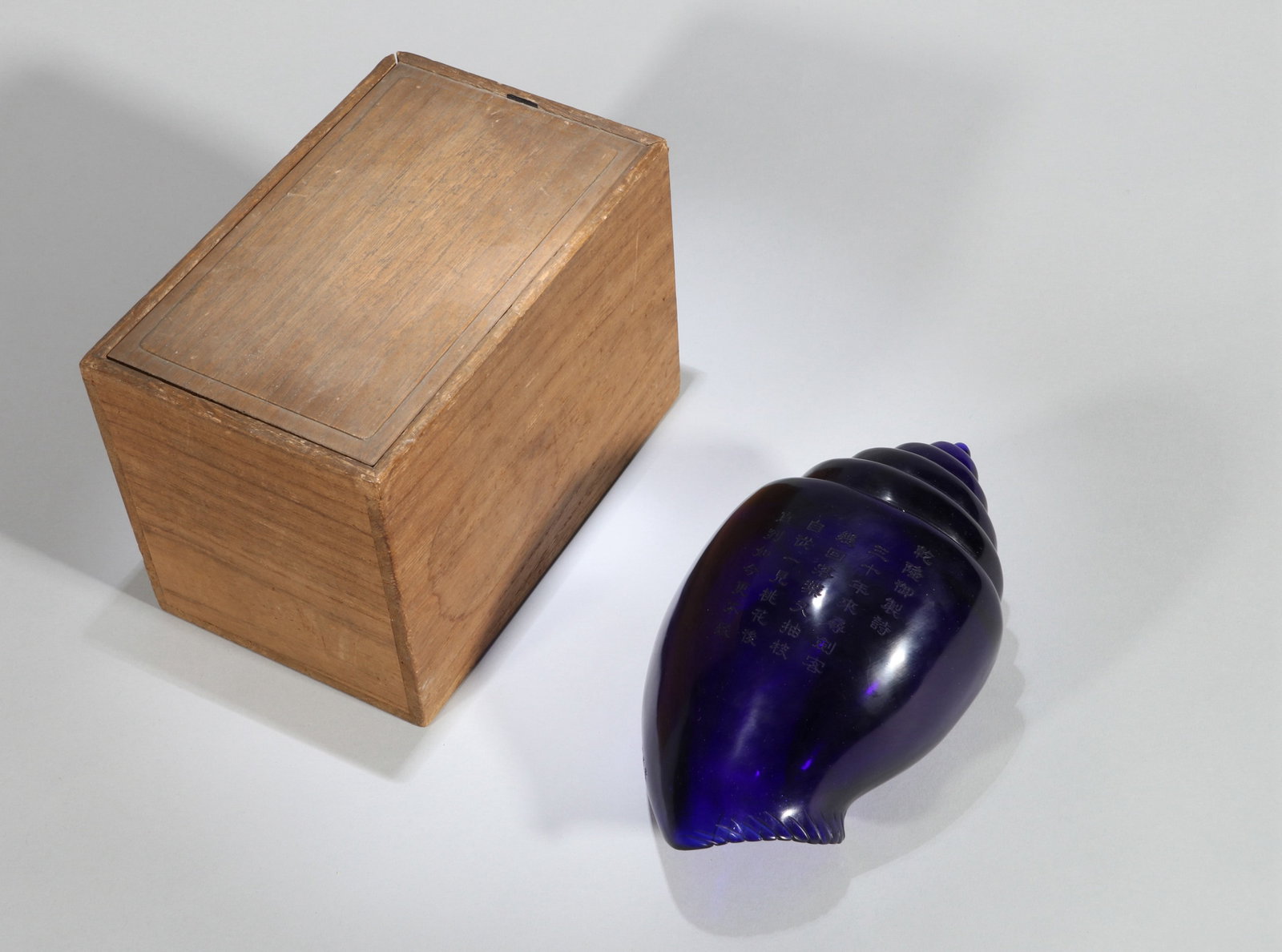 A BLUE GLASS RITUAL CONCH SHELL WITH POEM INSCRIPTION: A blue glass ritual conch shell with poem inscription. Length 18 cm.