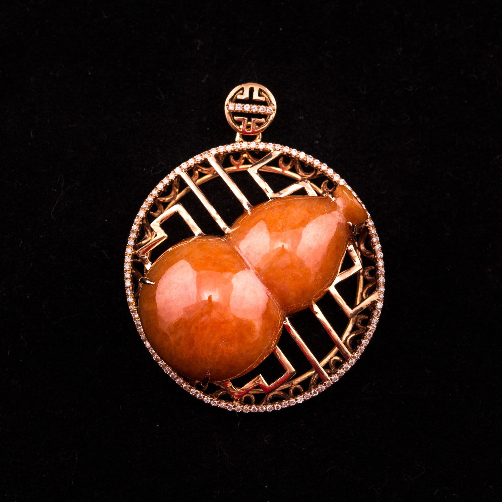 CINNABAR JADEITE, DIAMOND AND 18K ROSE GOLD PENDANT: Red jadeite with 18K rose gold pendant. A gourd-form cinnabar-color jadeite is inlaid in an 18K rose gold openwork base with numerous small diamonds. 1.25"h x 0.5"w x 0.75"l (3.18 x 1.27 x 1.91 cm)
