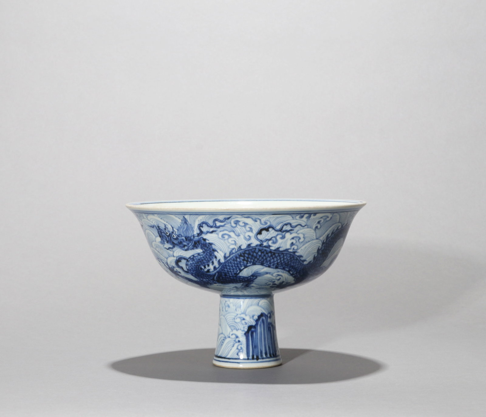 A BLUE-AND-WHITE STEM BOWL WITH A DRAGON ABOVE WAVES