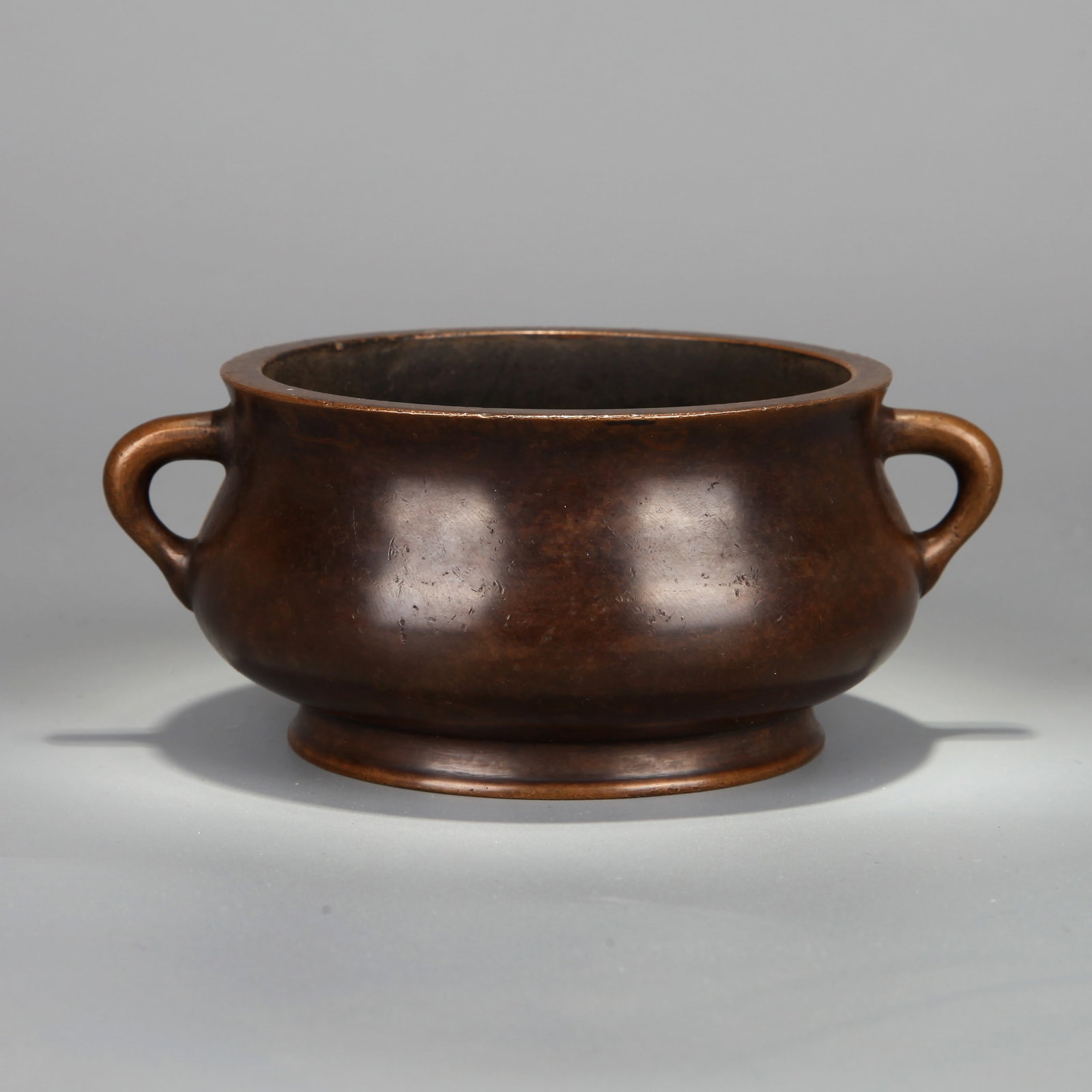 A TWO-HANDLED BRONZE CENSER: A two-handled bronze censer. Height 6 cm, width 13.8 cm, weight 710 g.