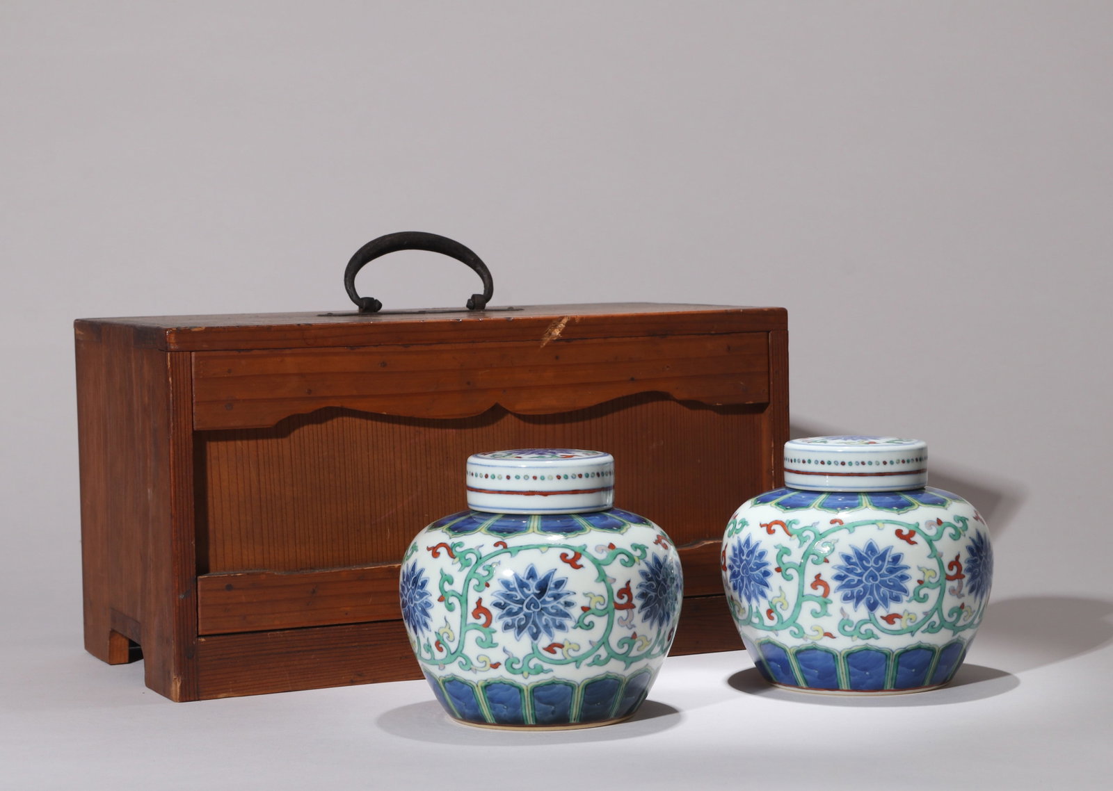 A PAIR OF DOUCAI 'LOTUS SCROLL' COVERED JARS: A pair of doucai covered jars with lotus scrolls. Height 11 cm.