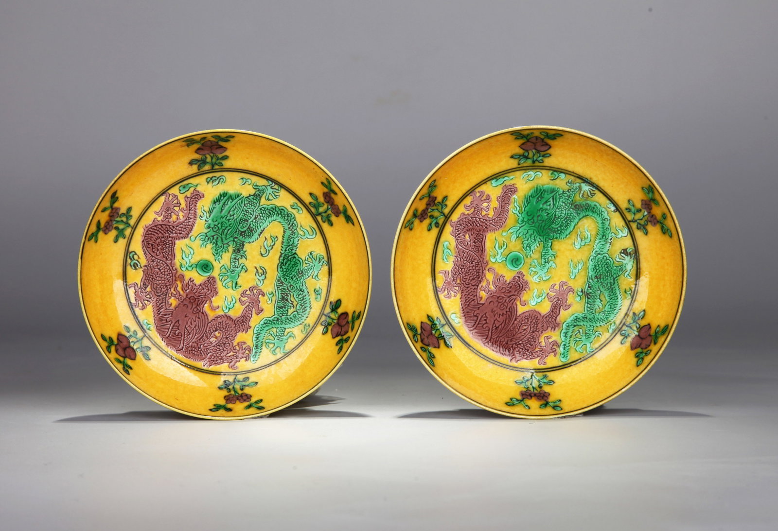 A PAIR OF YELLOW-GLAZED SANCAI 'TWO DRAGONS PURSUING A FLAMING PEARL' SAUCERS: A pair of yellow-glazed sancai saucers, each decorated with two dragons pursuing a flaming pearl. Diameter 11.2 cm, height 2.6 cm.