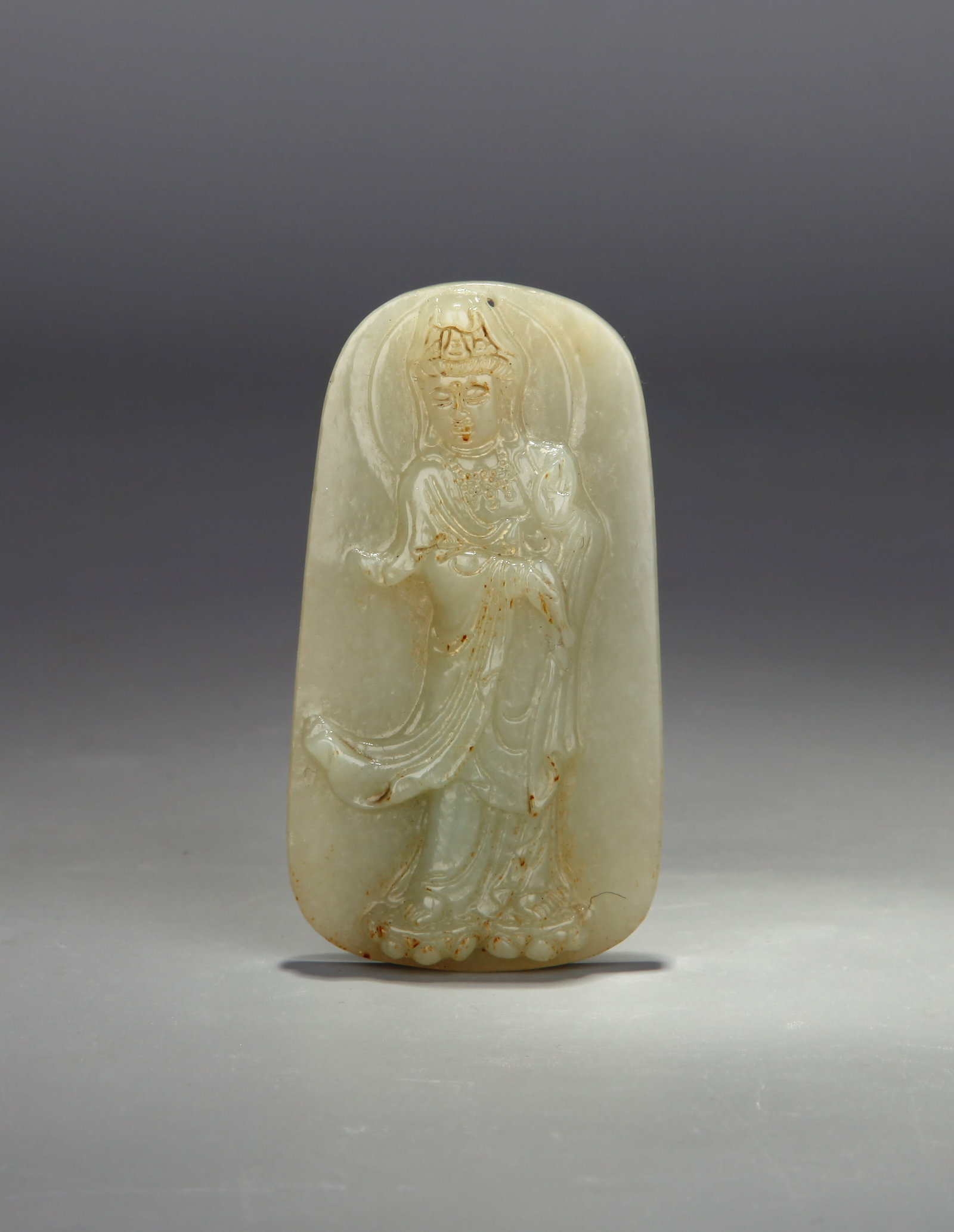 A WHITE JADE 'WATER-POURING GUANYIN' PENDANT: A white jade pendant carved with Water-Pouring Guanyin. Length 7 cm, width 3.7 cm, thickness 0.9 cm, weight 37.49 g.