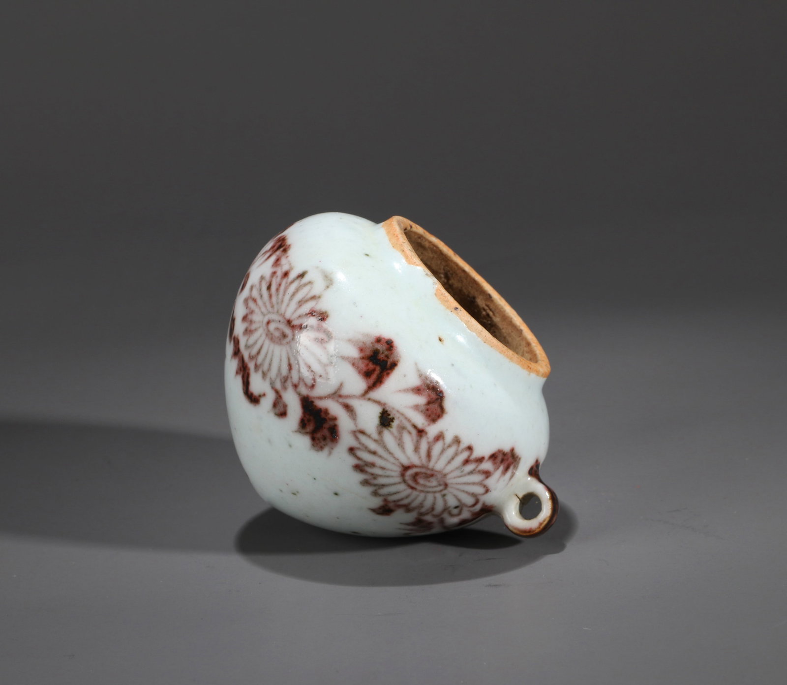 AN UNDERGLAZE-RED 'CHRYSANTHEMUM' BIRD FEEDER: An underglaze-red bird feeder decorated with chrysanthemum designs. Height 6.5 cm.