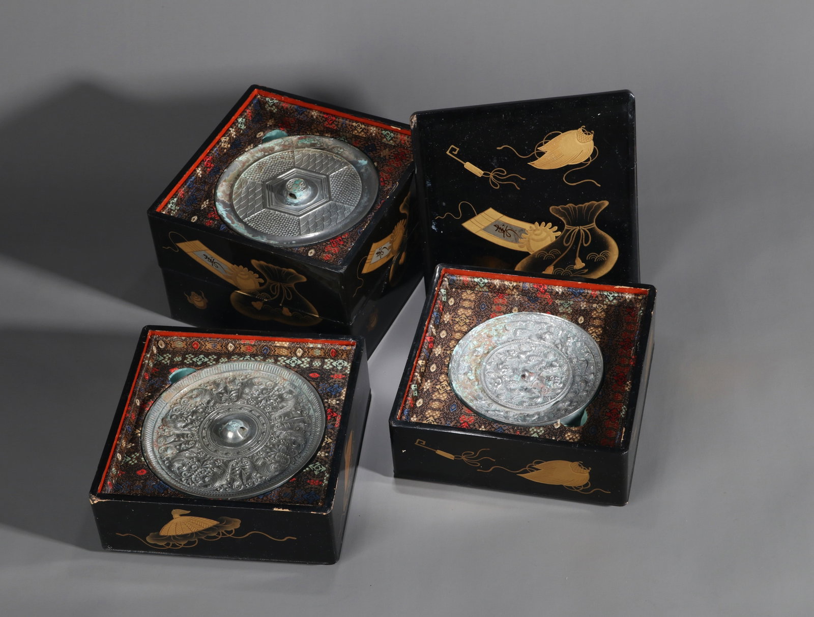 (LOT OF 4) BRONZE MIRRORS WITH SEA-BEAST AND MOUNTAIN DESIGNS: A group of four bronze mirrors with varied decoration, including examples with sea-beast and mountain designs. Diam. 13, 11, 12 and 12.5 cm. Note: With a black-lacquer and gilt stacking box.