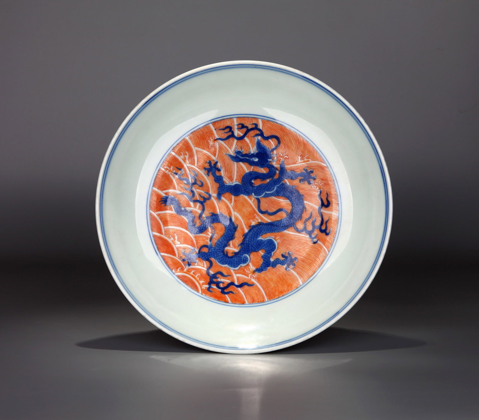 A BLUE-AND-WHITE AND IRON-RED 'DRAGON AMID WAVES AND CLOUDS' DISH: A blue-and-white and iron-red dish decorated with a dragon amid waves and clouds. Height 5.2 cm, diameter 15.5 cm.