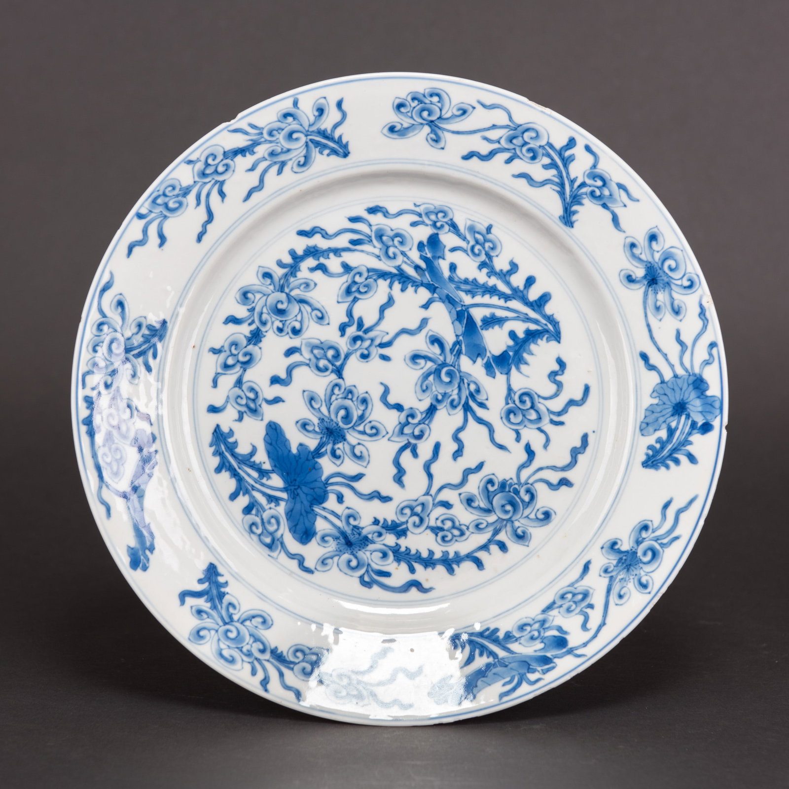CHINESE BLUE-AND-WHITE 'LOTUS' DISH, 18TH CENTURY: Chinese blue-and-white 'lotus' dish, 18th century. The shallow rounded dish is painted with lotus blossoms and leaves. A Chenghua mark is on the base. 1.38"h x 10.43"d (3.5 x 26.5 cm) Condition: With