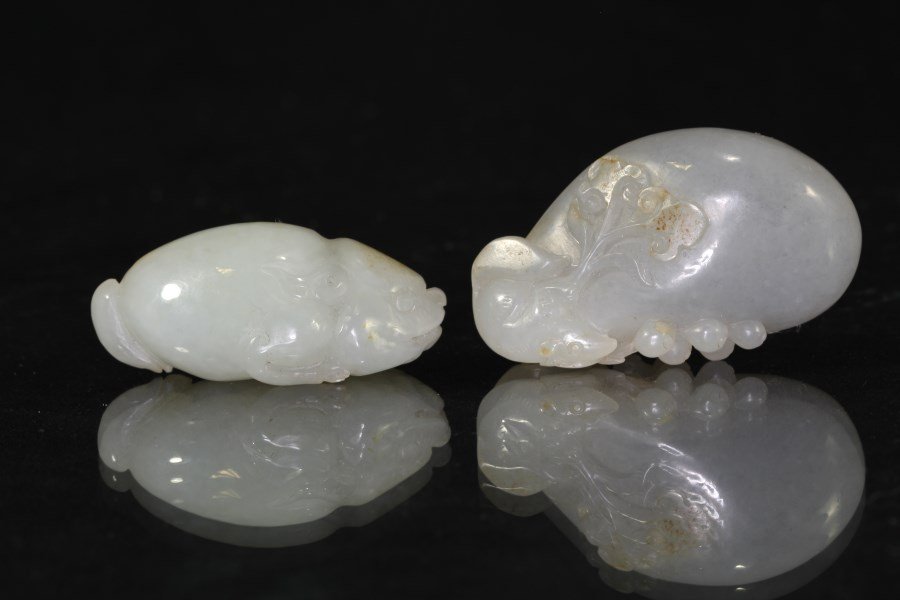 He Tian Yu (River Jade), 2 pieces: A set of two exquisite He Tian white jades, each with yellow hue inclusion, the first carved as a mythical animal, the second carved as a goldfish perched in pebble habitat. Length 1" Height 1.75"