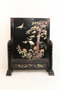 A Chinese Lacquered Wooden Table Screen: A Chinese Lacquered Wooden Table Screen, consisting of a central panel inset with painting of cranes and trees. The panel is mounted in another fame supported in a hardwood stand. Width 36" Height 42"