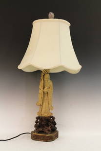 Chinese Soapstone Shoushan Stone Table Lamp: Chinese Soapstone Shoushan Stone Table Lamp, carved of a wise old man wearing flowing robes holding a peach on his left hand. It comes with champagne color lamp shield shade. Height 25.75"