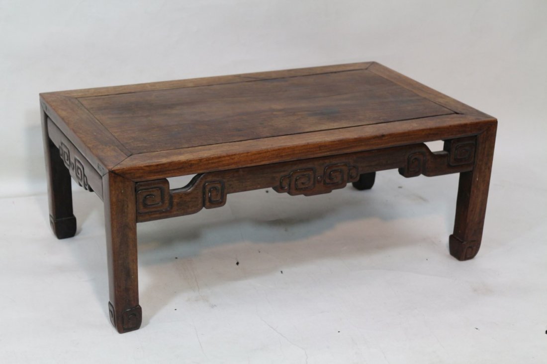 A Hardwood Tea Table: A Hardwood Tea Table, rectangular top with inset raised panel; over a floral pattern skirt leading to ends fitted with carved floral panels. Width 28" Depth 16.25" Height 11"